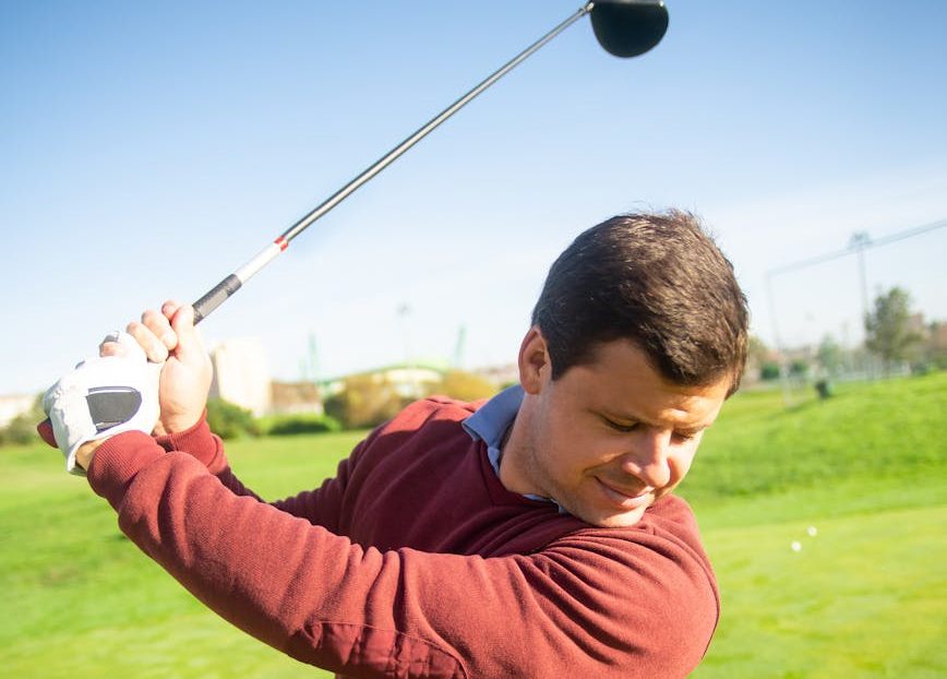 a man in maroon long sleeves playing golf